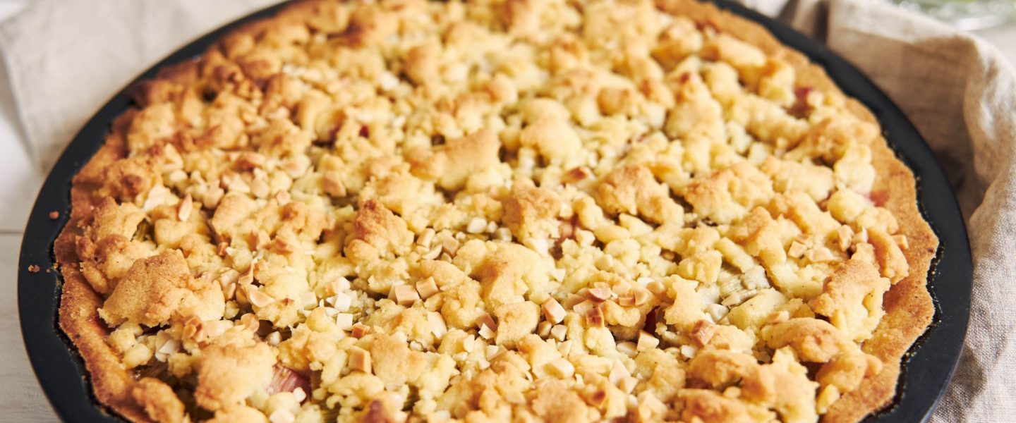 A vertical high angle shot of a plate of crispy Rhabarbar cake tart and some ingredients on a table