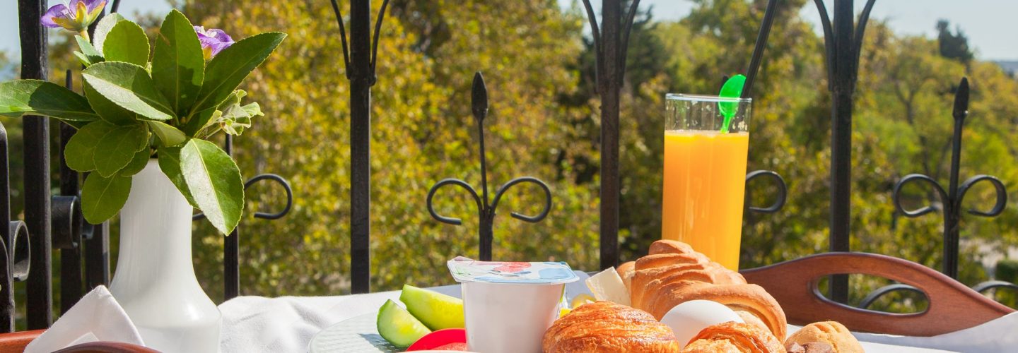 Croissant, boiled egg, orange juice breakfast on tray at balcony