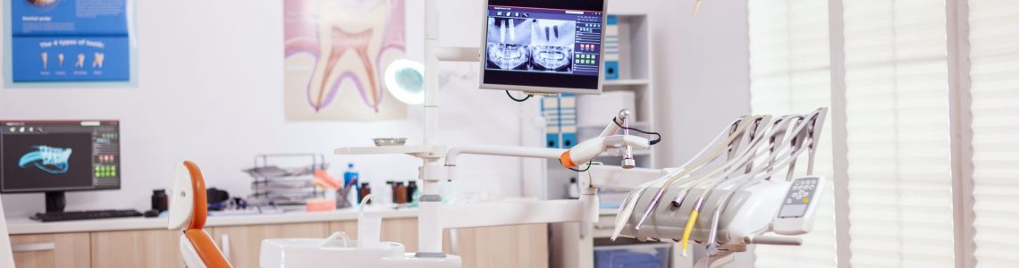 Dental chair and other accesorries used by dentist in empty cabinet. Stomatology cabinet with nobody in it and orange equipment for oral treatment.