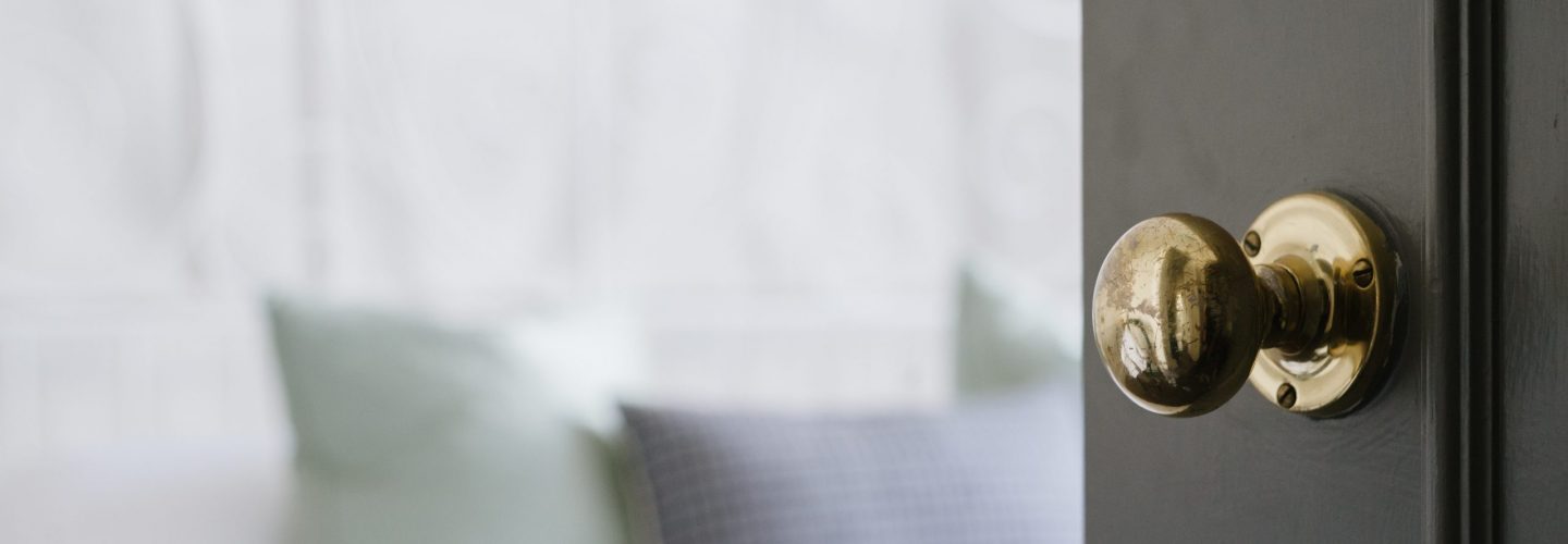 A closeup shot of a gold door knob on a black door